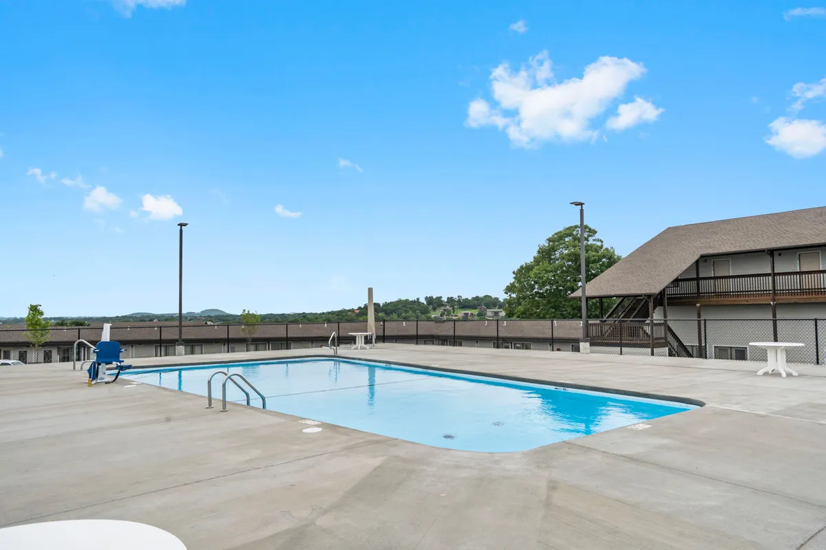 A sparkling outdoor swimming pool surrounded by lounge chairs and landscaped greenery. The scene evokes a leisurely, refreshing mood, perfect for swimming, sunbathing, or relaxing with family in the open air.
