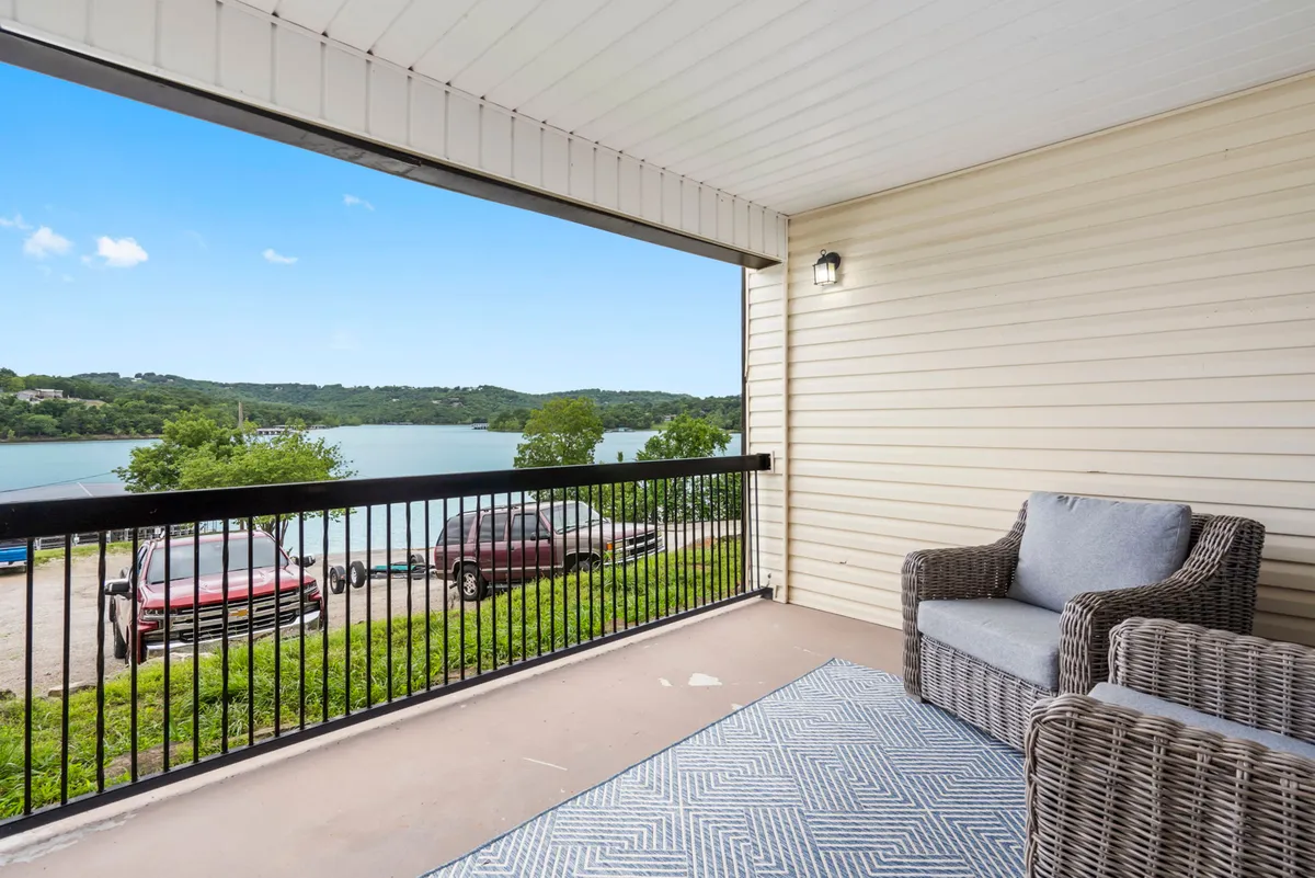 An inviting outdoor sitting area with a rug overlooks the lake, offering a serene spot for reading, socializing, or simply enjoying the view. The scene is peaceful and designed for small group gatherings or personal reflection.