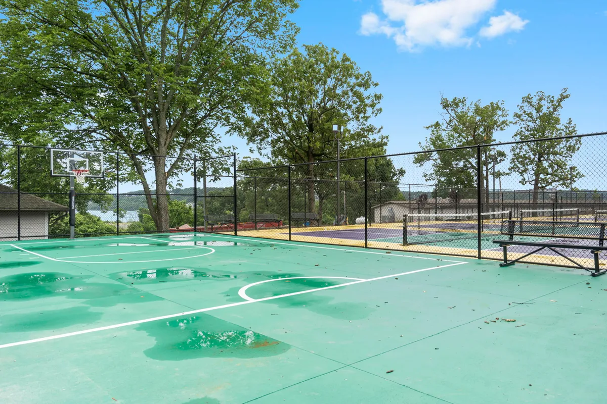 A dynamic basketball court surrounded by tall trees and benches, inviting families and friends for outdoor games, picnics, and gatherings. The court is well-maintained and situated in a green, energetic environment.