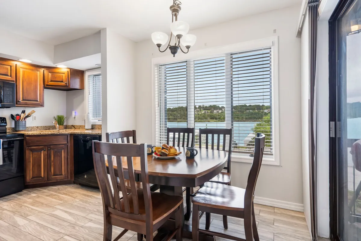 A sunlit dining area with a spacious dining table set beside large windows, offering scenic sunrise views and bringing the outdoors in. The inviting setting features elegant kitchen cabinetry and subtle décor, making it ideal for family meals, casual gatherings, or morning coffee in a bright, cheerful atmosphere.